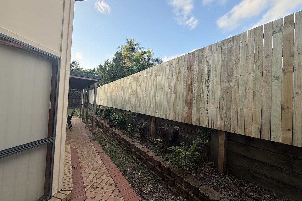 Timber paling fence running the full length of a side boundary past a house