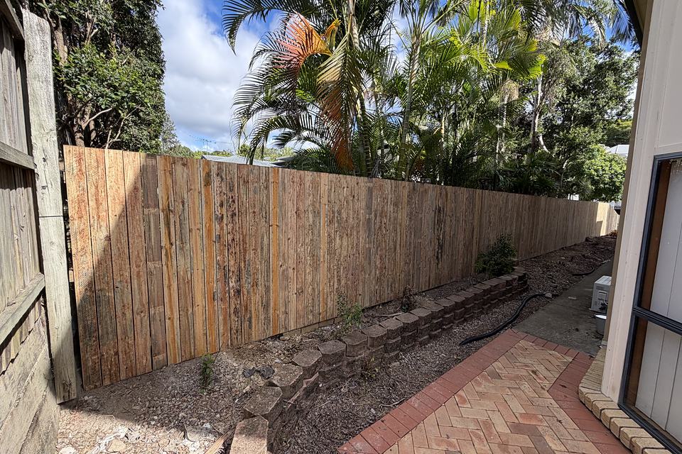 Timber fence held level across sloping ground on a stepped sleeper course