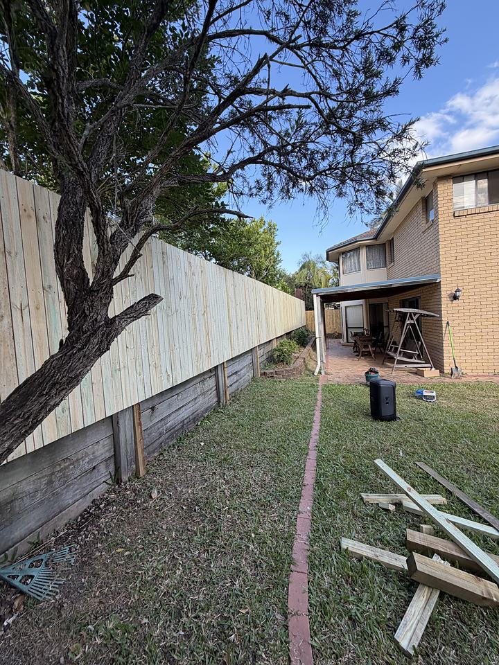 A timber fence part way through construction with materials laid out on the grass